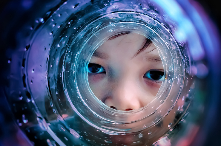 Kid staring at us through a glass tube