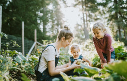 Woman with two girls looking at a vegetable in a garden