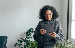 Standing woman looking at a tablet in a living room